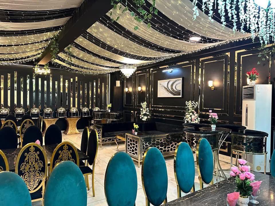 Hall dressed for a reception with teal and gold seating under draped fairy lights