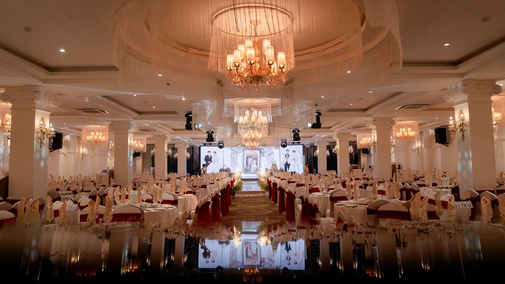 Elegant wedding banquet hall set with tables, chandeliers and a stage