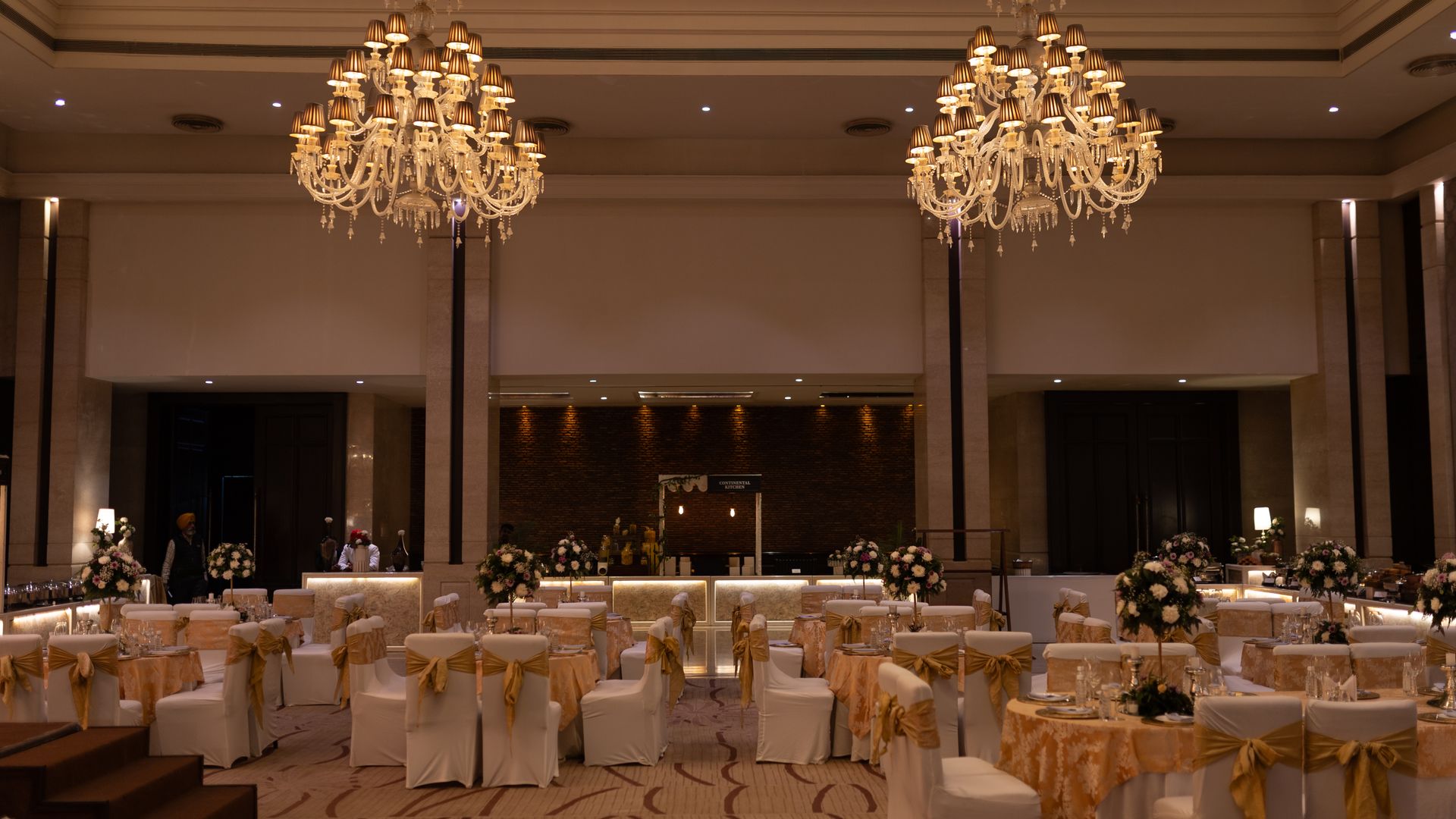 Grand ballroom set for a celebration with chandeliers and floral centrepieces